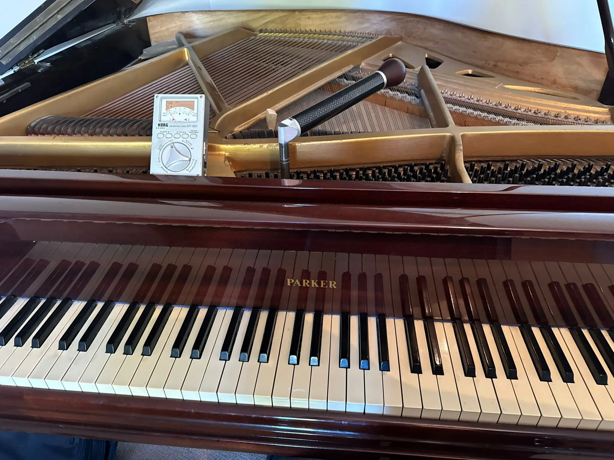 A tuning lever on the pins of a piano with an electronic tuner on the frame