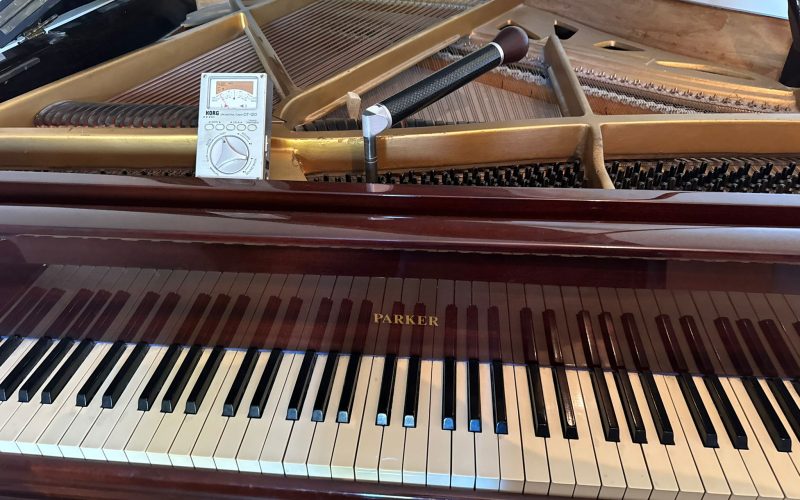 Close-up of open grand piano showing interior strings and tuning equipment.
